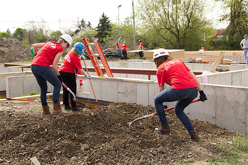 Three Value crew members using shovels to dig around the home