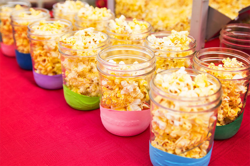 Mason jars filled with popcorn sitting on a red table 