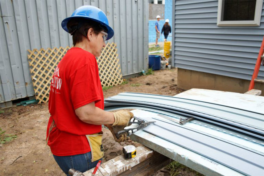 A woman using tools to cut siding