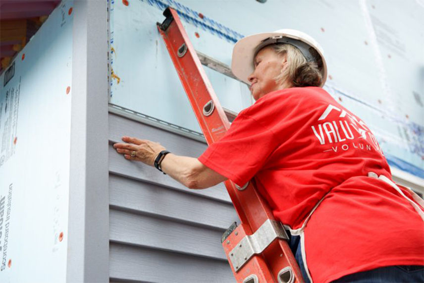 A Woman from the Valu Home Centers installing siding on the house