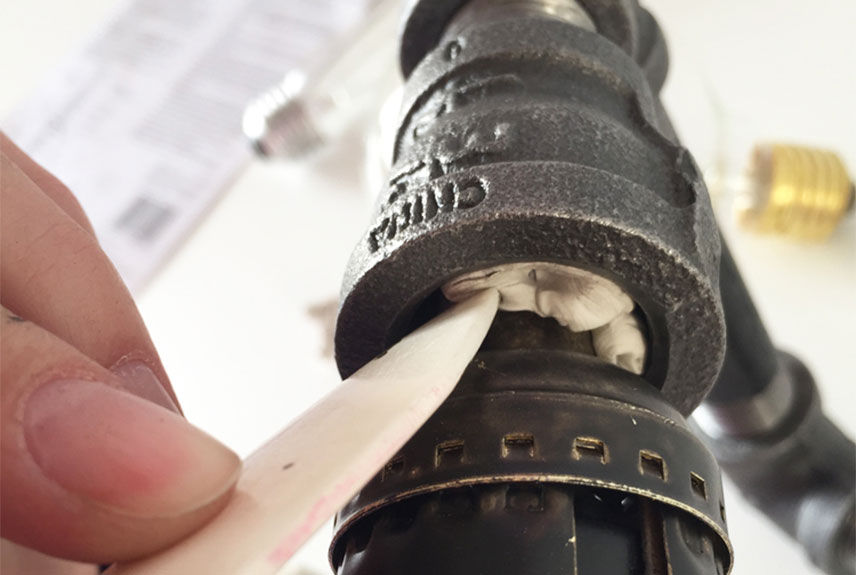 pressing sticky tack with a bone folder inside the piping of the light fixture