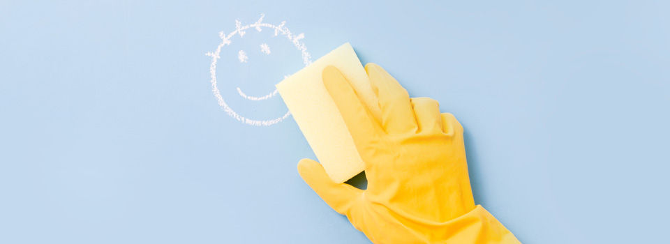 A person cleaning a painted wall wearing a rubber glove
