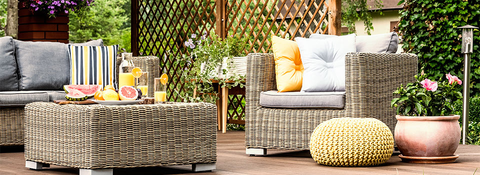 Grapefruit and orange juice on table on wooden terrace with yellow pouf next to armchair