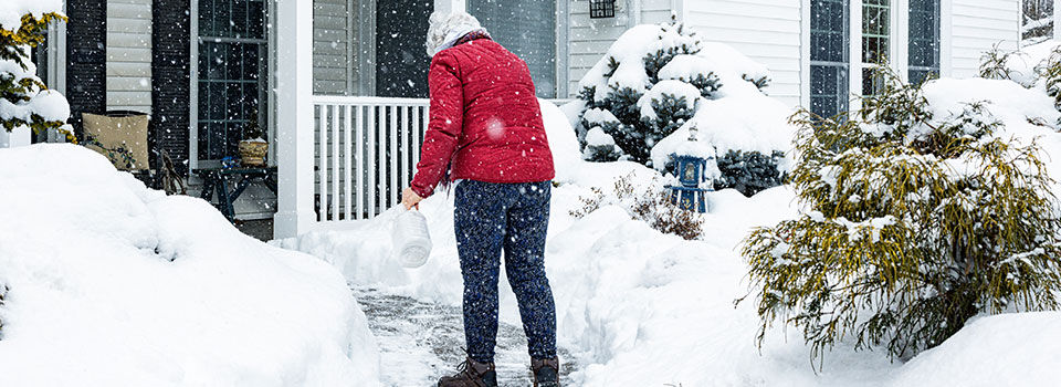 Woman spreading ice melt on a cleared walkway