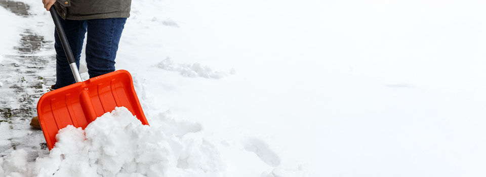 Woman with shovel cleaning snow. Winter shoveling. Removing snow after blizzard.