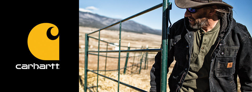 A middle aged man on a ranch moving a green gate wearing a cowboy hat and a Carhartt jacket