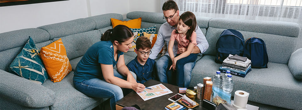 Mother explaining to her family the assembly point map while preparing emergency backpacks