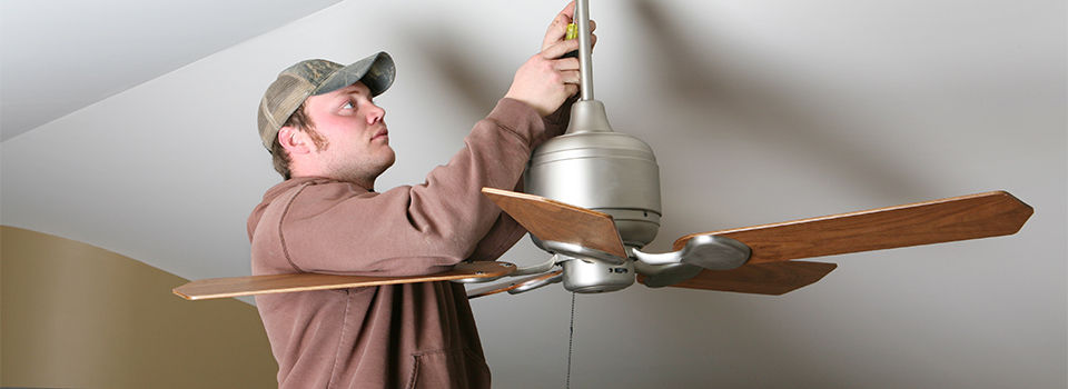Electrician installing energy-saving ceiling fan on home addition job.