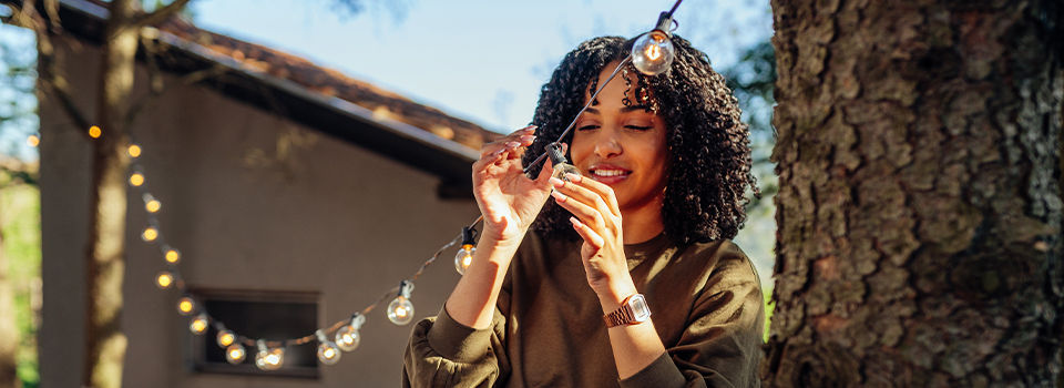 A woman hanging outdoor string lights