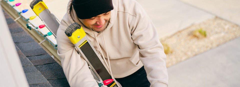 Person hanging up christmas lights outside