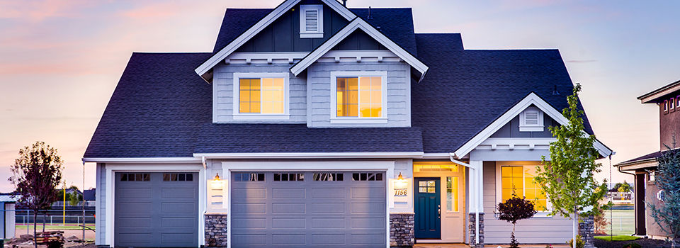 exterior of a house with it's lights turned on inside with the sunset in the background