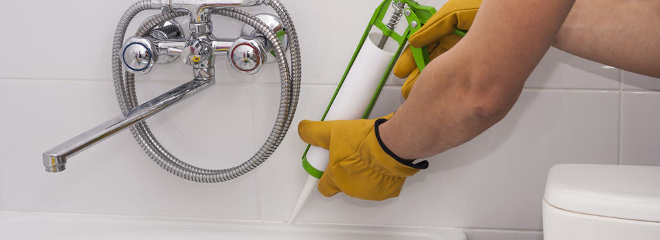 a person caulking a bathroom