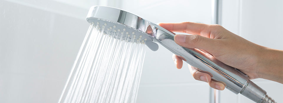 Close-up of female hands holding hand shower