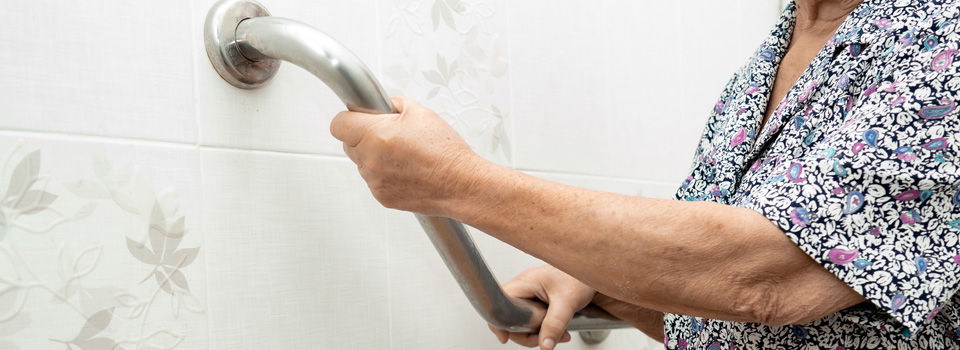 elderly woman holding on to bathroom safety bar