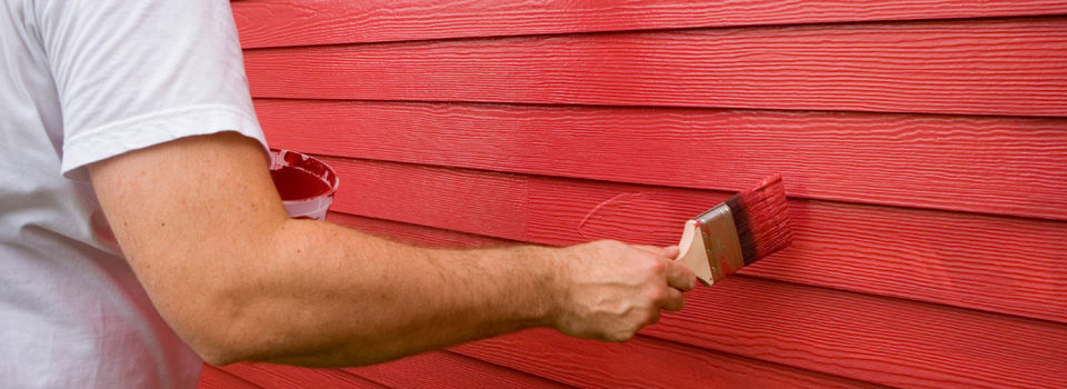 a man painting vinyl siding red