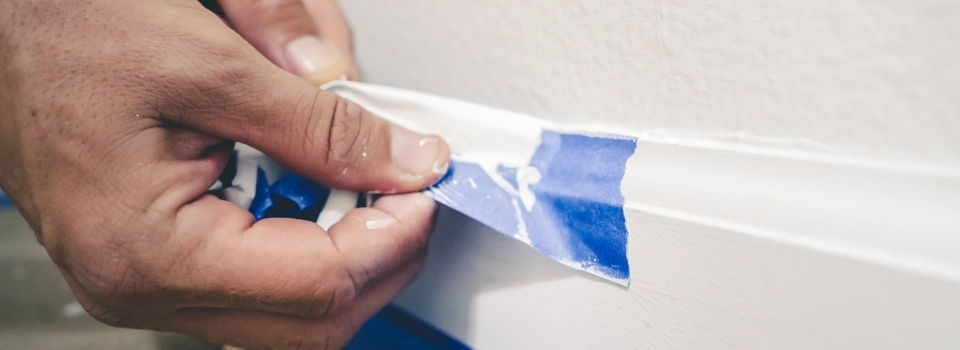 Blue tape applied to white moulding for paint preparation