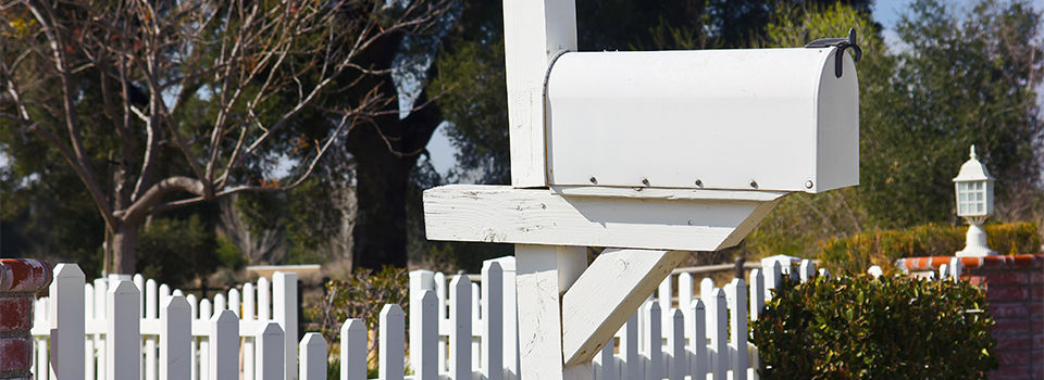 A mail box next to a white picket fence