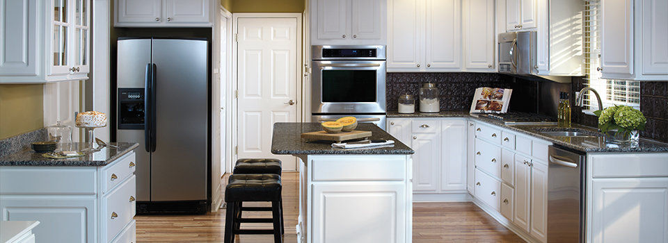 Kitchen with white cabinetry, black countertops, and stainless steel appliances