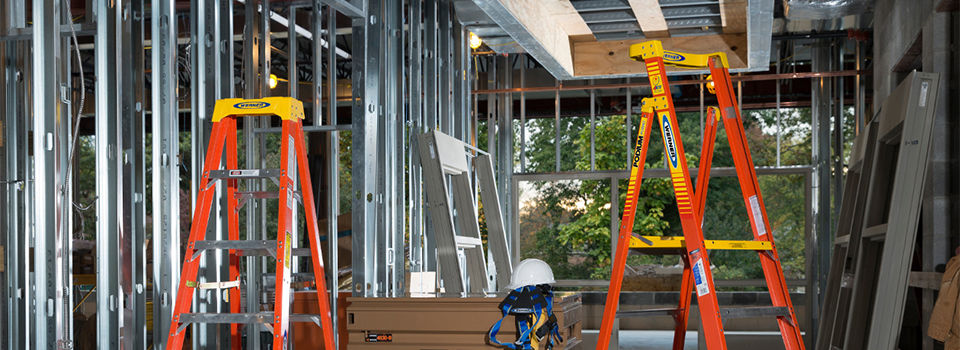 Two orange and yellow Werner ladders placed in the center of a construction site.