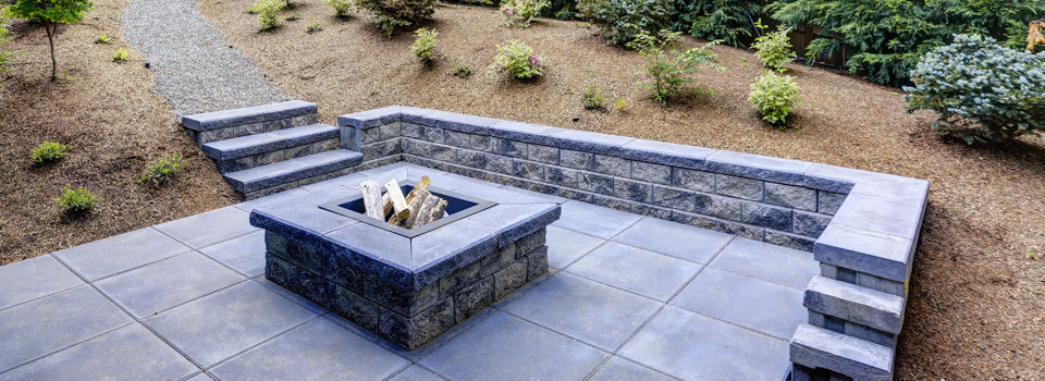 Concrete paver and slate patio framed by mulch and shrubs