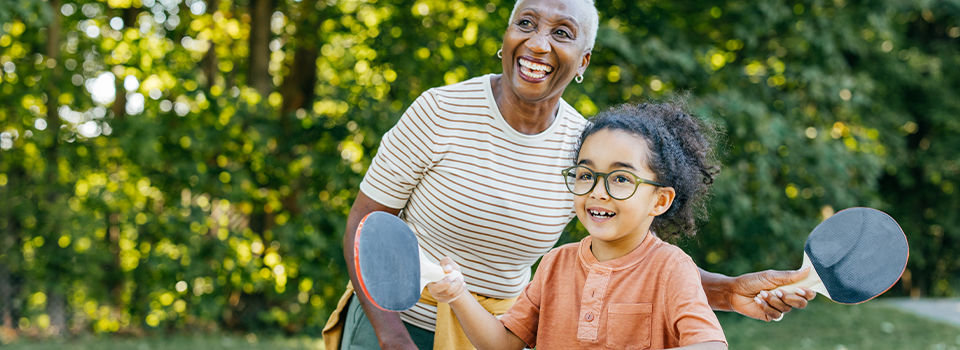 A woman and a child playing ping pong outdoors 