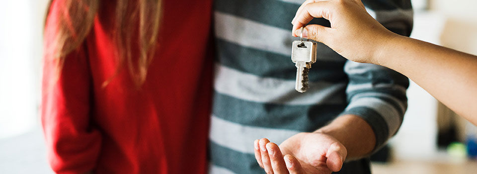 A person handing keys to a couple