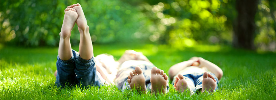 Group of happy children lying on green grass outdoors in spring park.