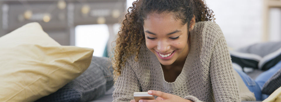 teenager on phone in tidy dorm room
