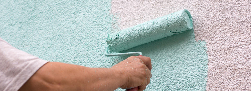 a person painting a stucco wall with a paint roller