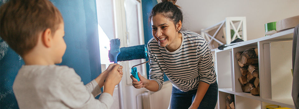 A mother and child painting a room together