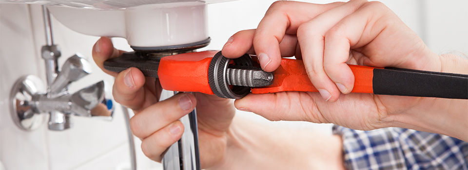 Portrait of male plumber fixing a sink in bathroom