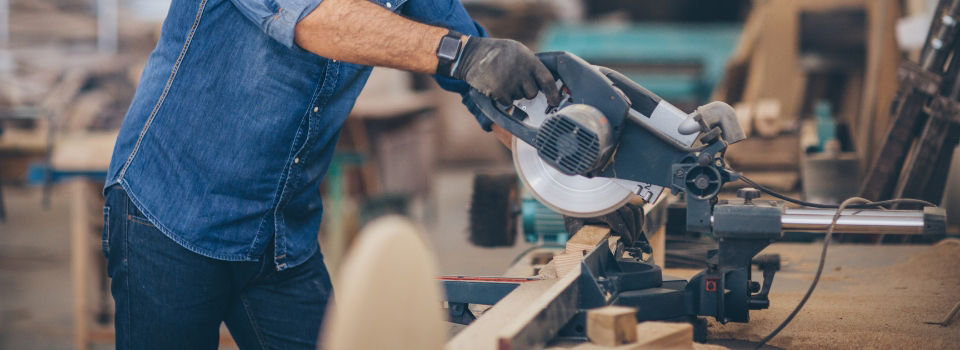 Table saw cutting lumber while operated by man wearing protective gear
