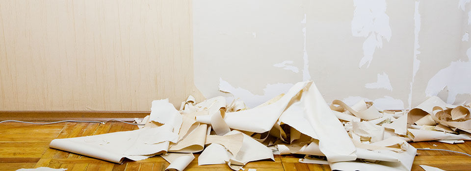 A pile of torn down old wallpaper sitting on a hardwood floor ready to be thrown away