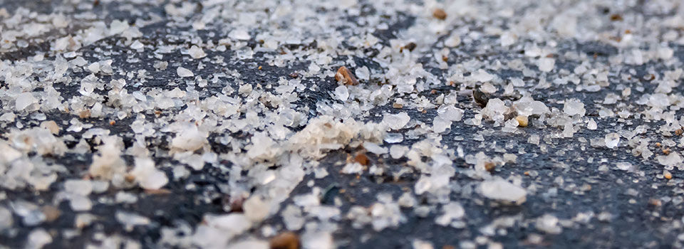 Macro shot of salt grains on icy sidewalk surface in the winter