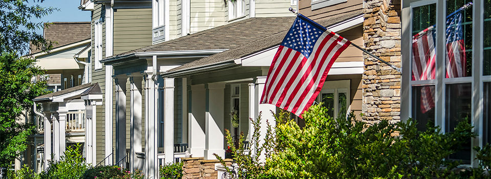 American Flags hang from the front of this traditional, brick homes in an All-American neighborhood.