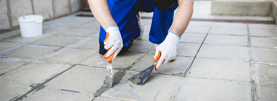A man repairing the grout on a tile floor.