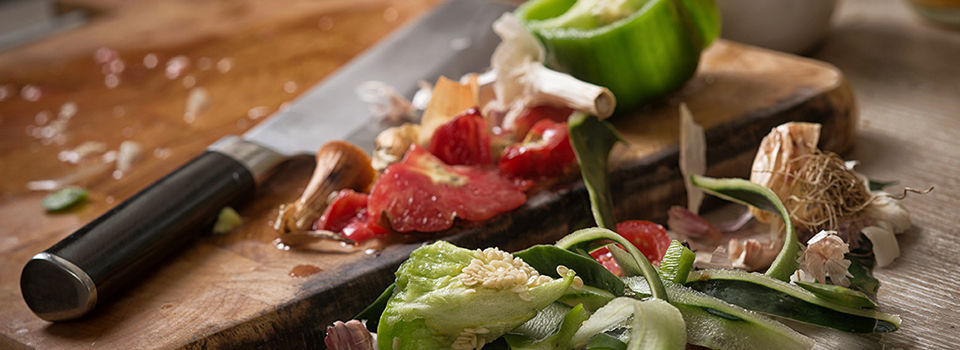 Knife and veggie scraps laying on a cutting board