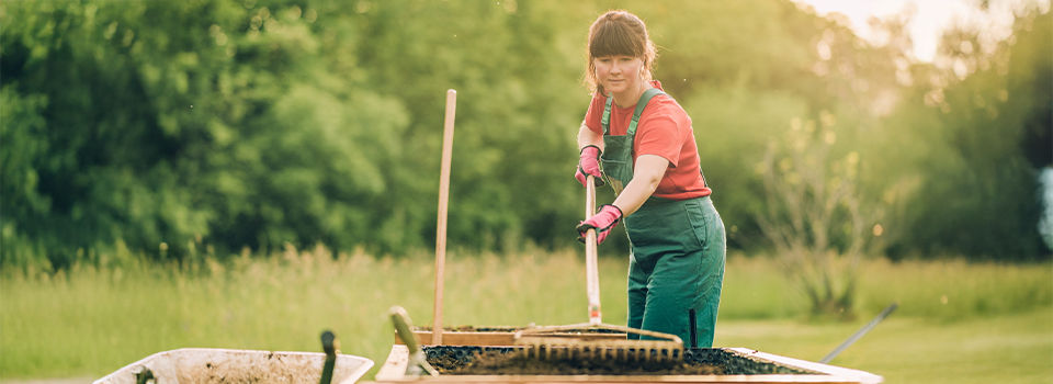 Woman filling a new constructied raised garden bed with fresh soil