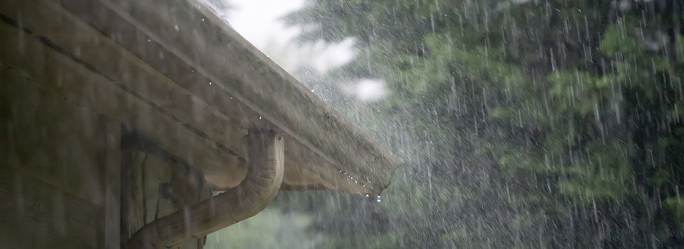 Close up of heavy rain pouring on the gutters of a residential home during a passing storm.