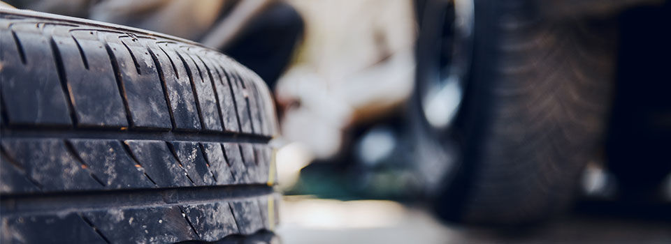 Close-up of a vehicle tire with a vehicle in the background blurred