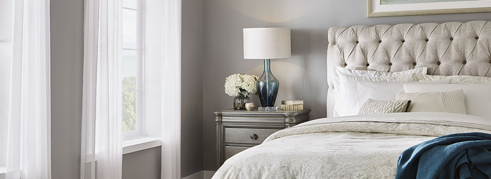 Curtains open and sun shining into bedroom with a side table beside the bed