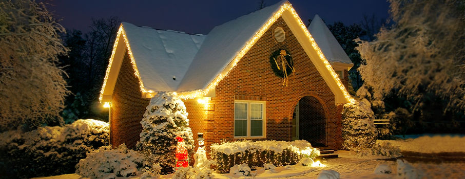 A snowy winter home in the evening with Christmas lights and Christmas decorations outside