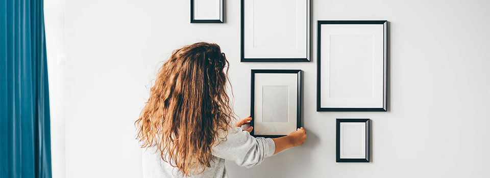 Woman straightening empty picture frame on the wall
