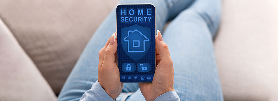 Person holding their smart phone while on the couch with a home security app pulled up