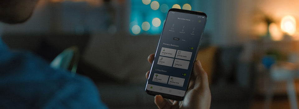 Someone holding a phone with the mobile leviton decora smart app pulled up on the screen
