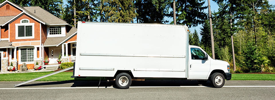 White moving box truck parked don the side of the street in front of a house