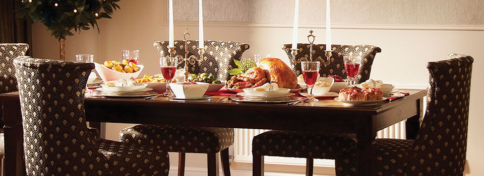 Dining room table set up with a cooked turkey, side dishes, and glasses of wine