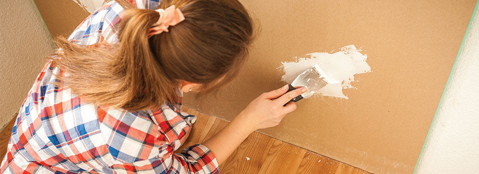 Woman patching a hole in the wall