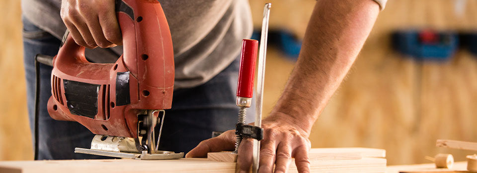 Carpenter cutting a wood using jigsaw cutter