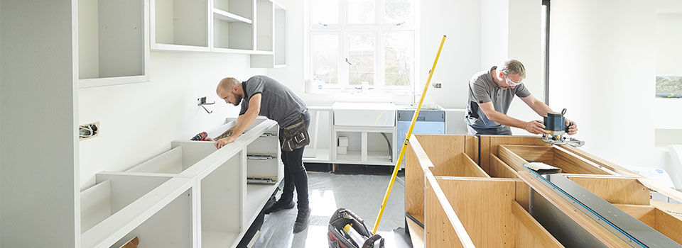 Two contractors working on an unfinished kitchen